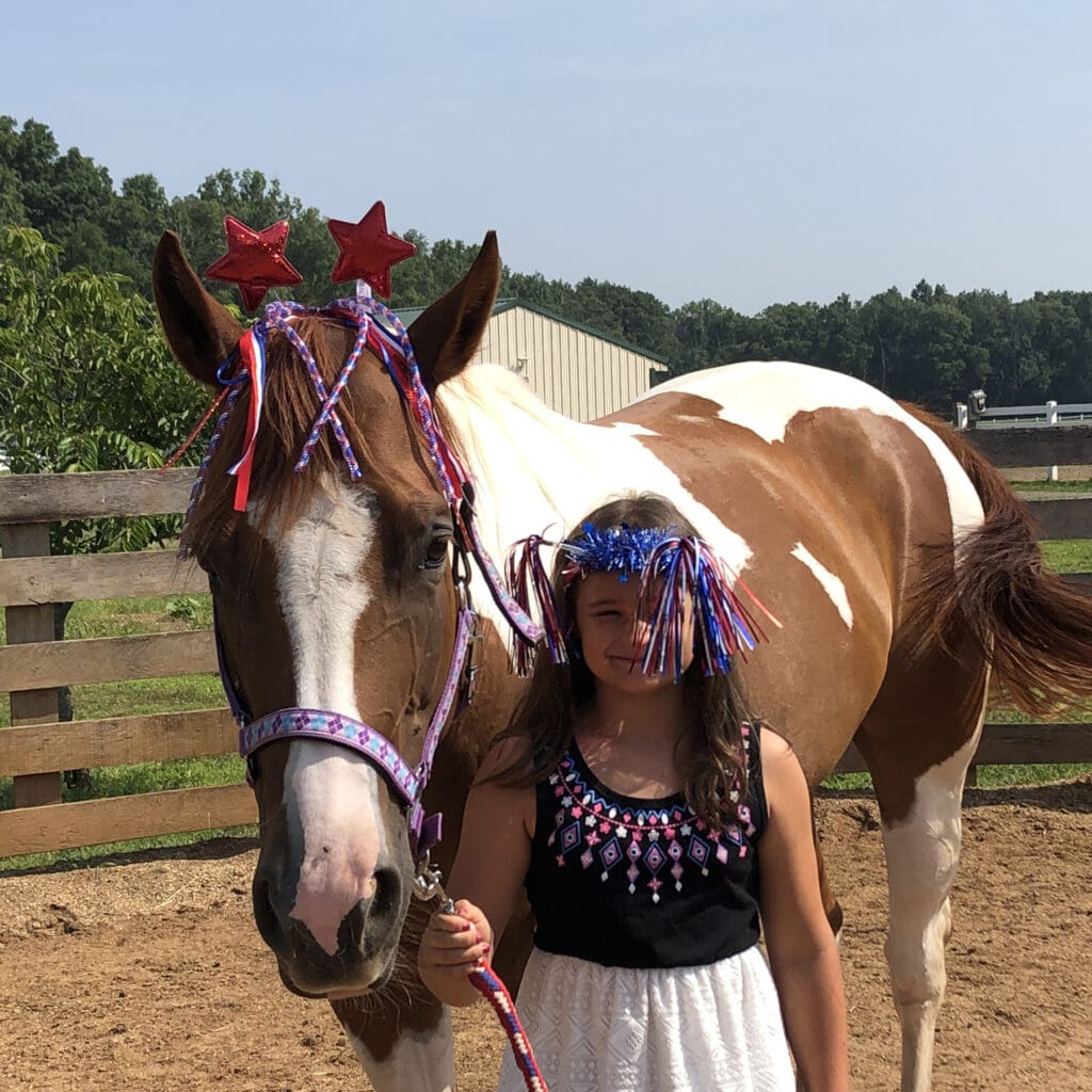 Girl standing with brown and white horse